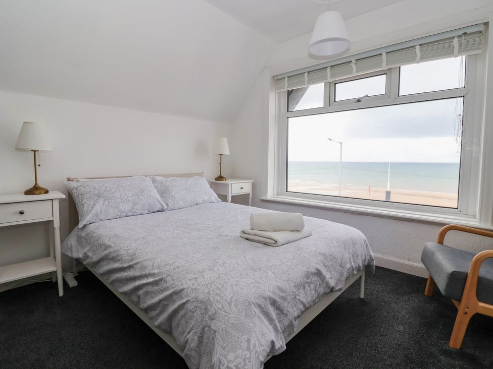 A bedroom with a bed and window overlooking the sea at Sunrise Lodge in Bridlington