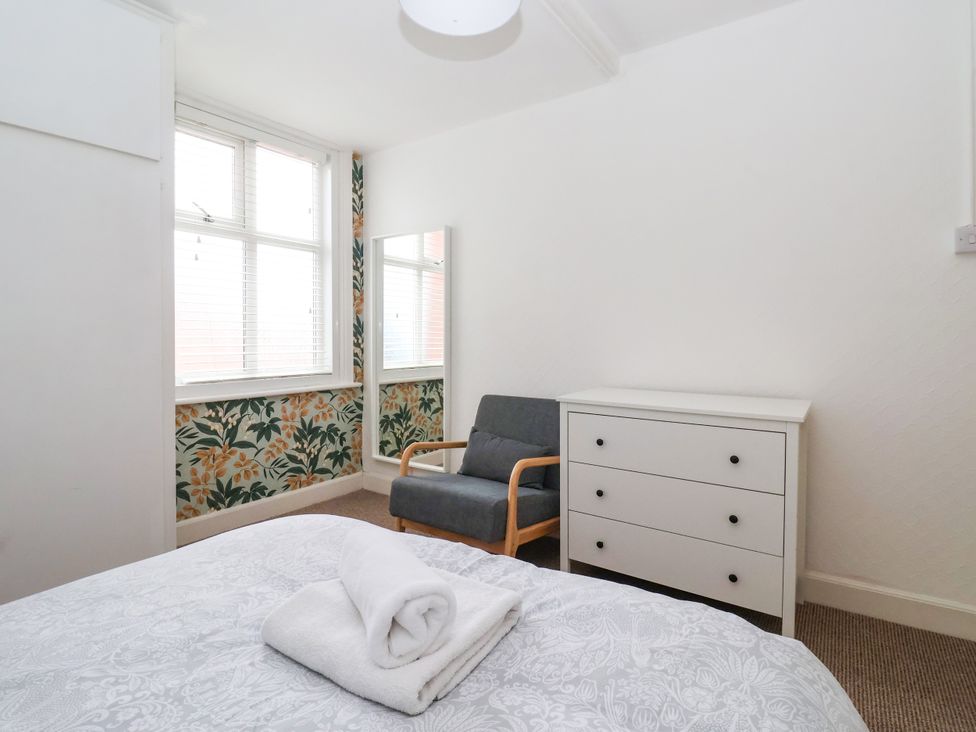 A bedroom with a bed, towel, chair, mirror, and dresser at Sunrise Lodge in Bridlington