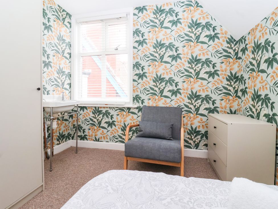 A bedroom with a chair, sink, and drawer chest at Sunrise Lodge in Bridlington