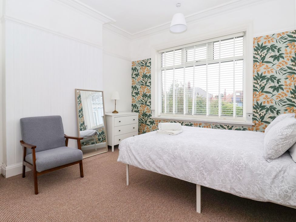 A bedroom with a bed, mirror, chair, and dresser at Sunrise Lodge in Bridlington