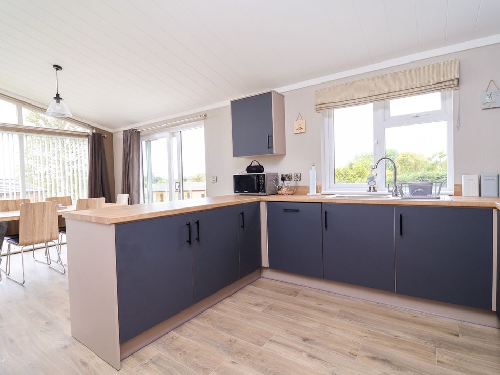 A kitchen with cabinets and a dining area at Beach Lodge in Lloc