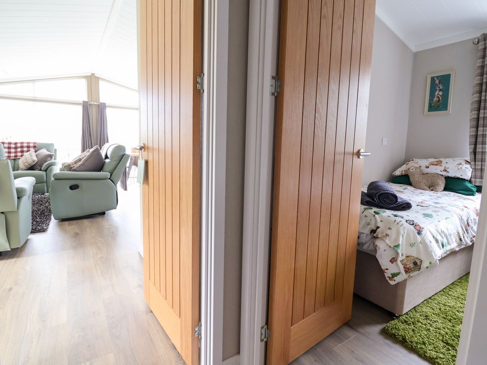 A living room with a view through an open door to a bedroom at Beach Lodge in Lloc