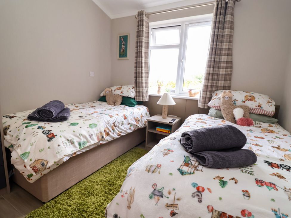 A bedroom with two single beds and a lamp at Beach Lodge in Lloc