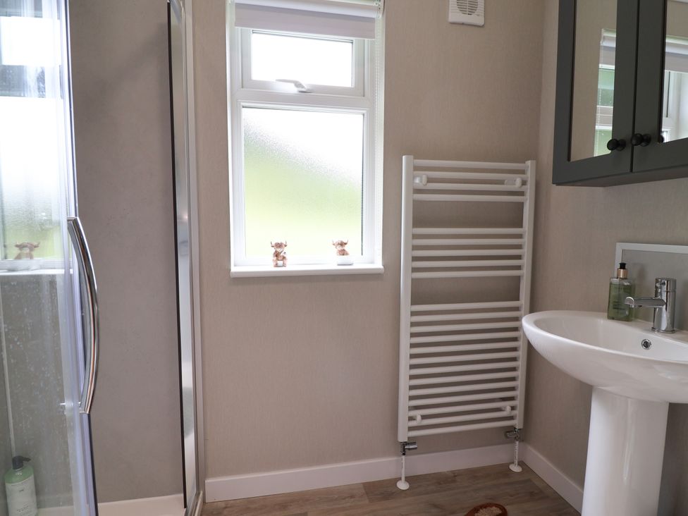 A bathroom with a shower, sink, and towel radiator at Beach Lodge in Lloc
