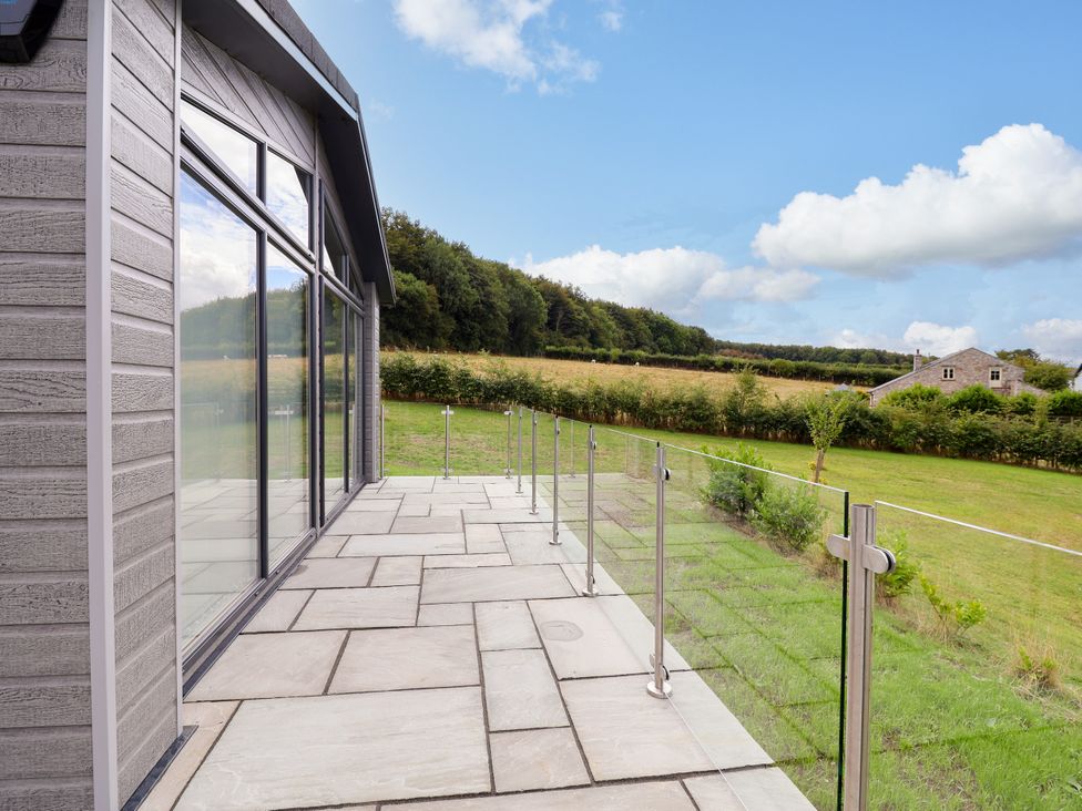 An outdoor patio with a glass railing at Beach Lodge in Lloc