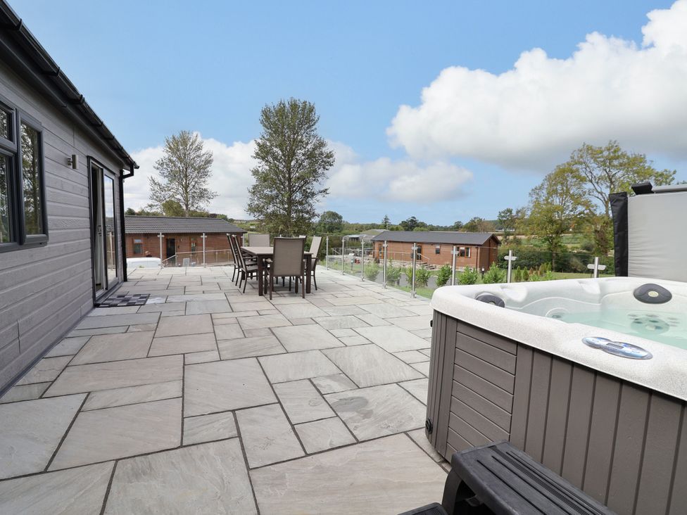 An outdoor patio with a hot tub and seating area at Beach Lodge in Lloc