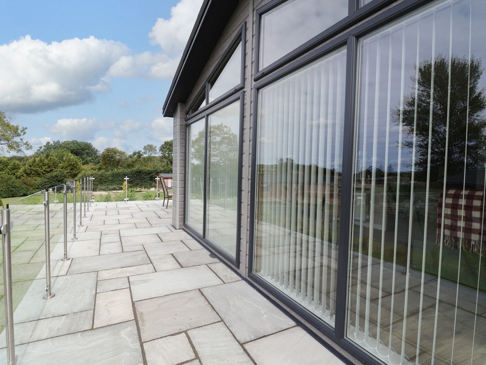 An outdoor area with a patio and large windows at Beach Lodge in Lloc