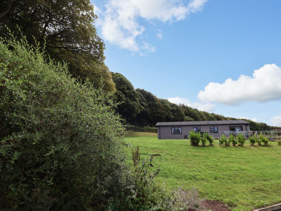 A building on grass with trees and clouds at Beach Lodge in Lloc