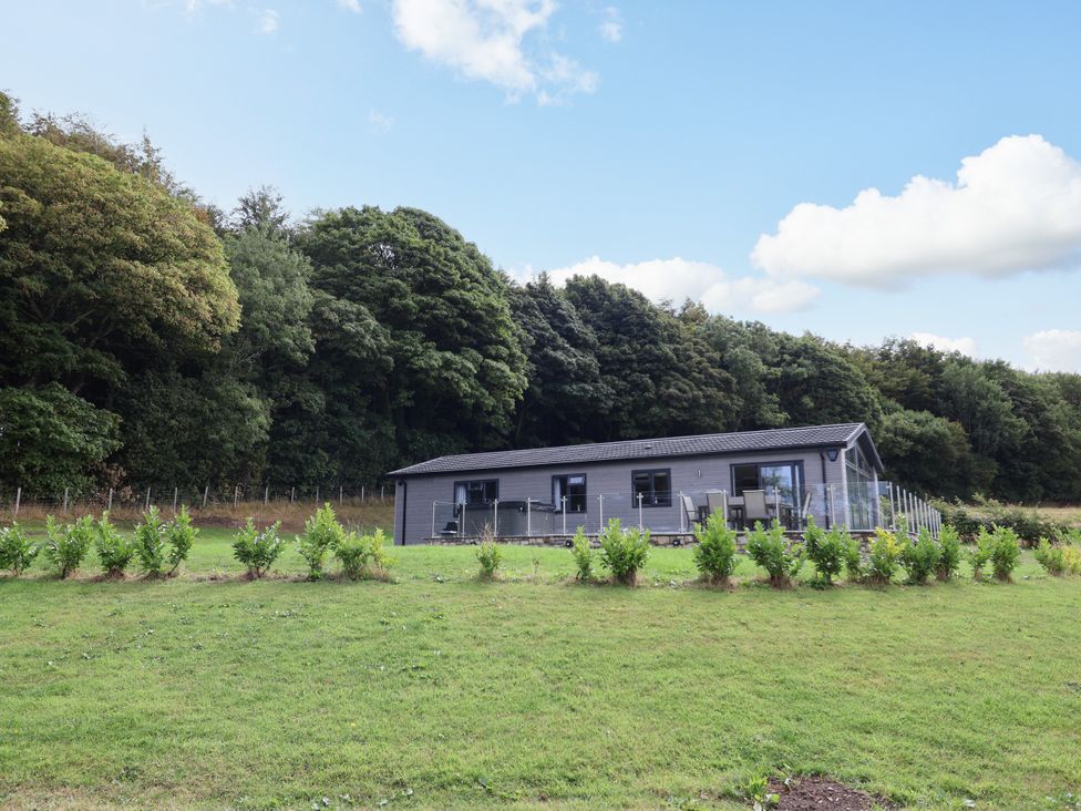 A house with a deck and trees in the background at Beach Lodge in Lloc