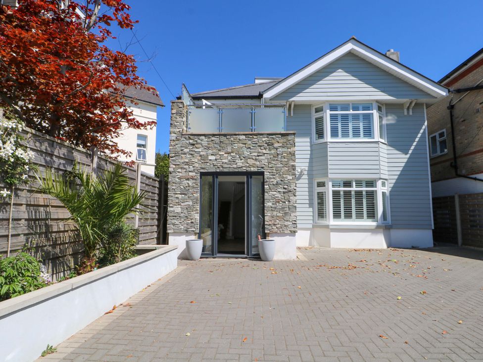 A house exterior with stone wall and glass railing at Shoreline Retreat Bournemouth