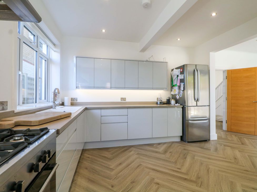 A kitchen with cabinets, a fridge, a stove, and a window at Shoreline Retreat in Bournemouth