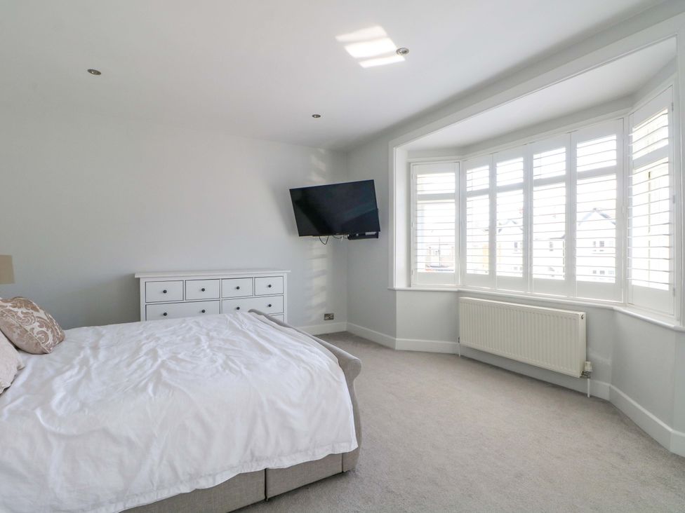 A bedroom with a bed, dresser, and television at Shoreline Retreat in Bournemouth