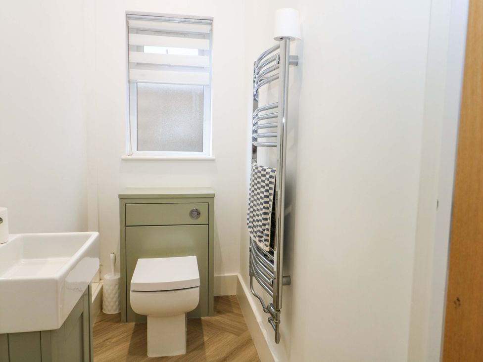 A bathroom with a toilet, sink, and towel radiator at Shoreline Retreat Bournemouth