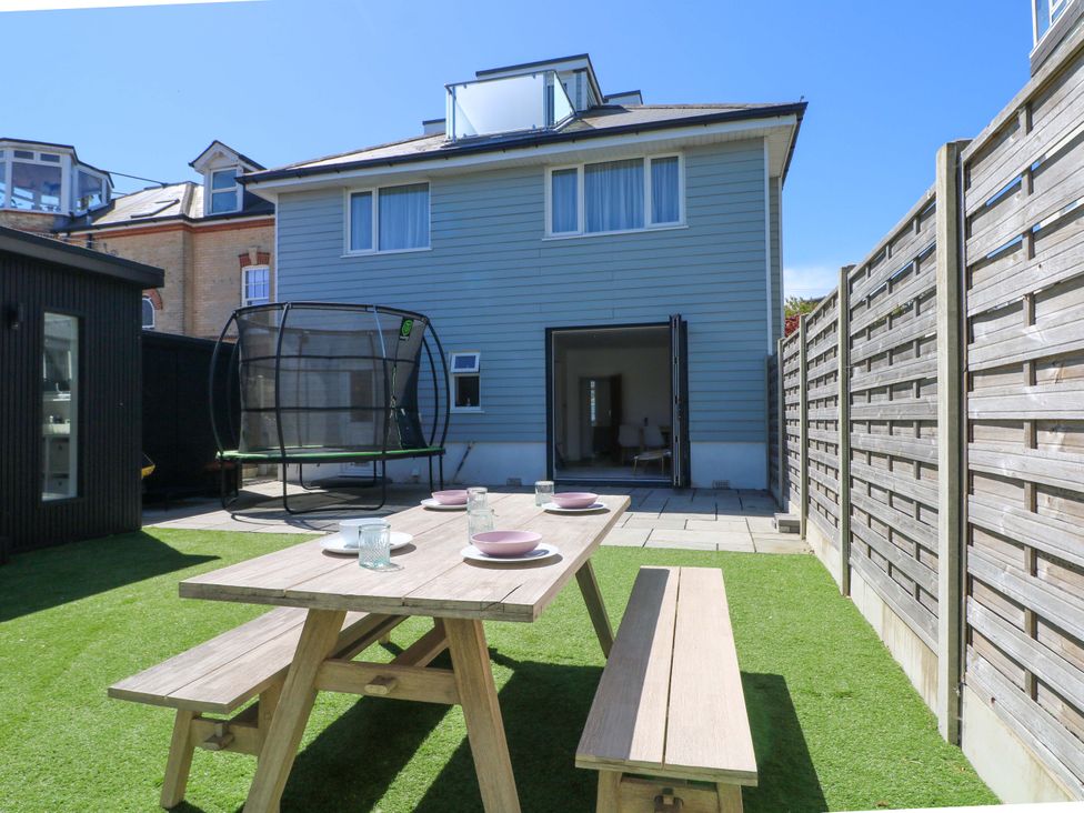A garden with a table set for dining and a trampoline at Shoreline Retreat in Bournemouth