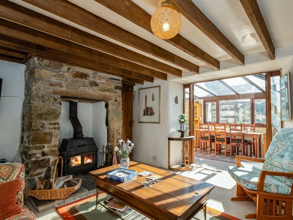 A living room with a fireplace and wooden table at Trehaverock Cottage in St. Endellion near Port Isaac