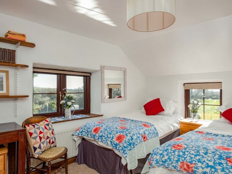A bedroom with two beds and a bookshelf at Trehaverock Cottage St. Endellion near Port Isaac
