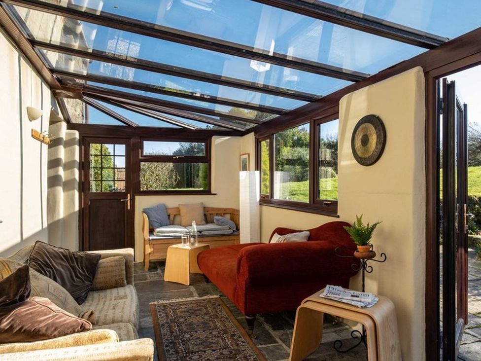 A conservatory with seating and a glass ceiling at Trehaverock Cottage St. Endellion near Port Isaac