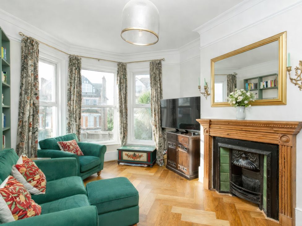 A living room with a green sofa and a television at 19 East Cliff Gardens in Folkestone