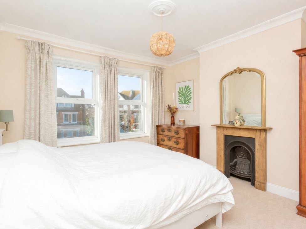 A bedroom with a bed and windows at 19 East Cliff Gardens Folkestone