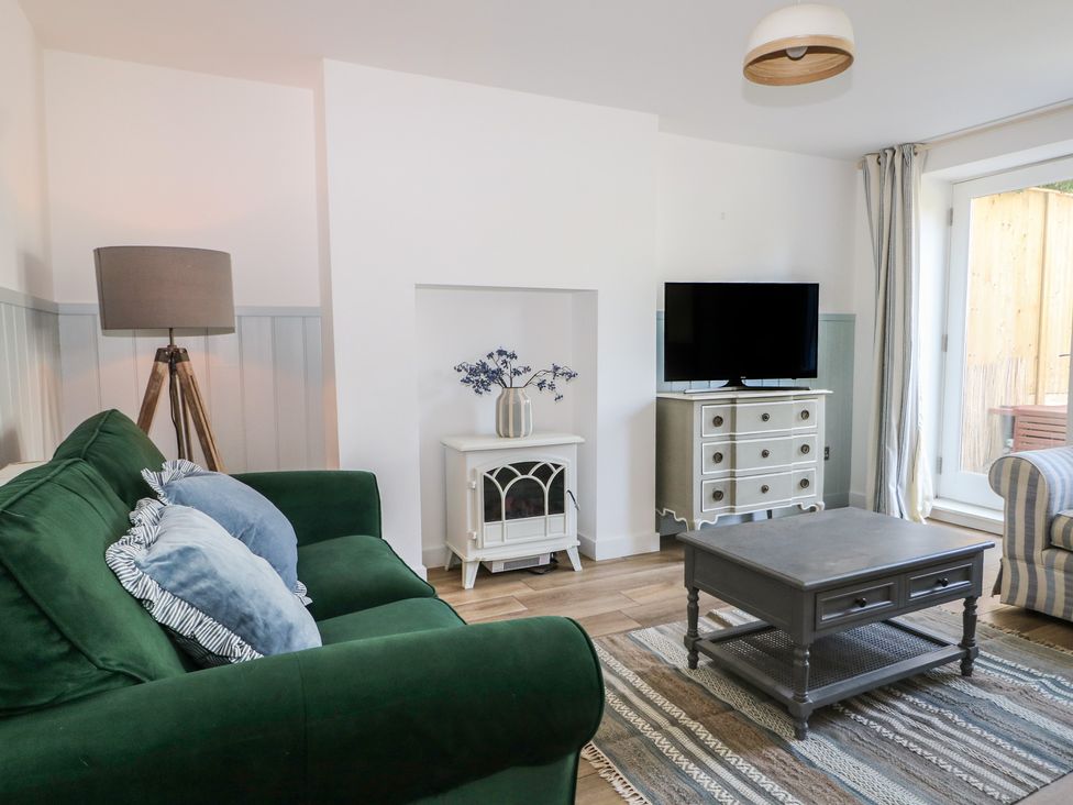 A living room with a green sofa and a television at East Cliff Gardens in Folkestone