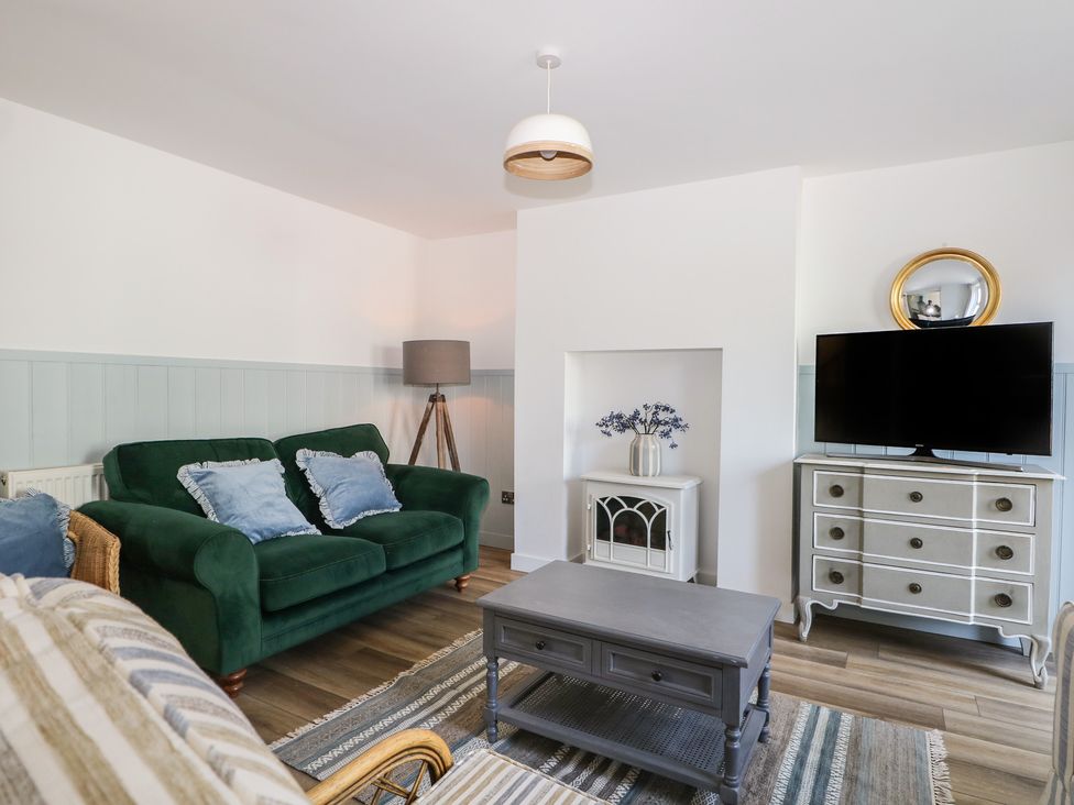 A living room with a green sofa and television at East Cliff Gardens in Folkestone