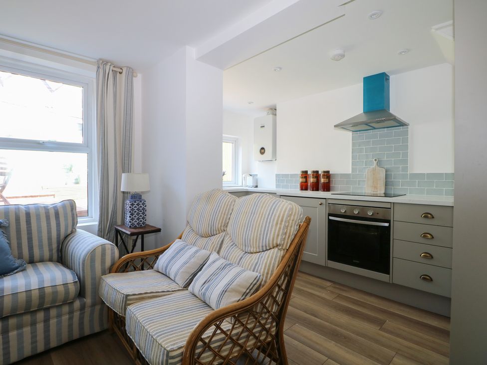 A living room with a sofa and armchair next to a kitchen at East Cliff Gardens in Folkestone
