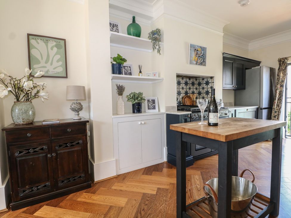 A kitchen with a table and wine bottles at East Cliff Gardens in Folkestone