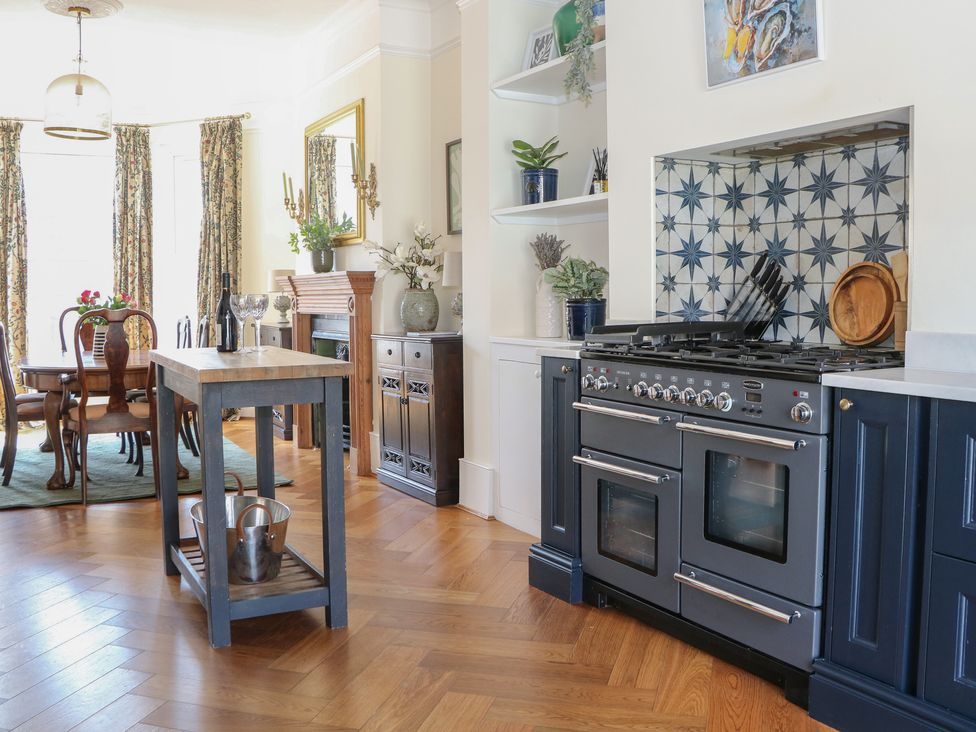 A kitchen with a dining table and stove at East Cliff Gardens in Folkestone
