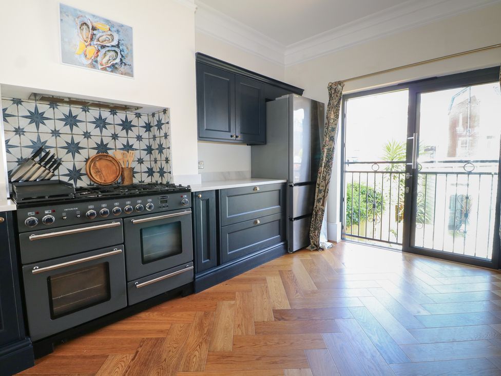 A kitchen with cabinets, oven and refrigerator at East Cliff Gardens in Folkestone