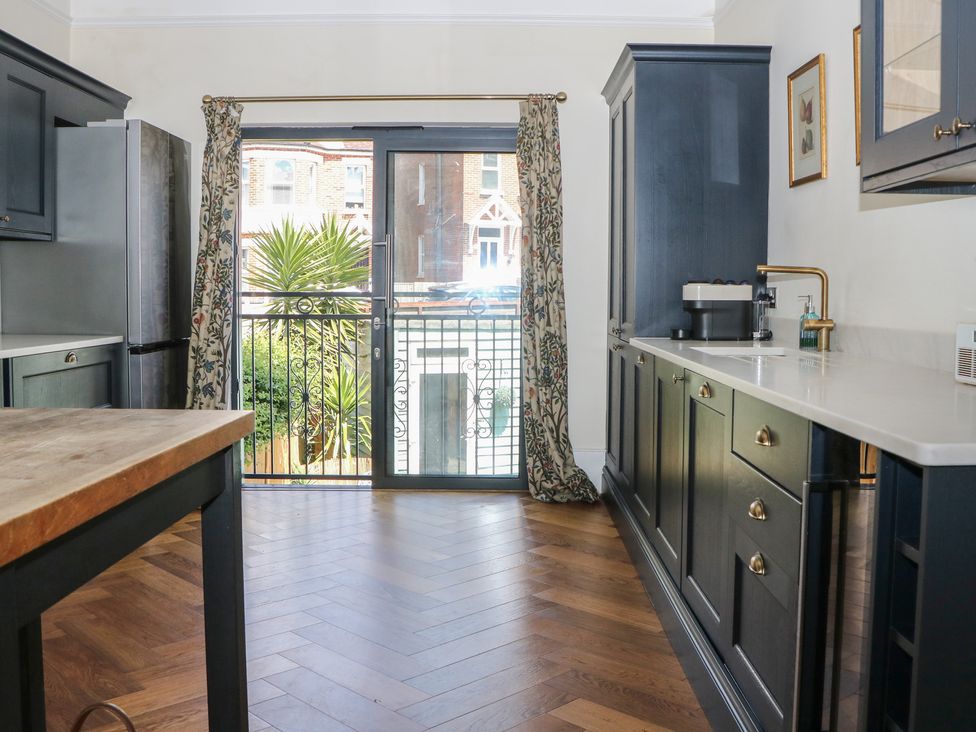 A kitchen with a balcony door and refrigerator at East Cliff Gardens in Folkestone