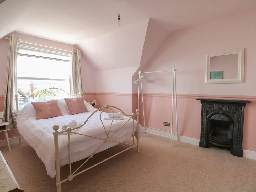 A bedroom with a bed, clothes rack and fireplace at East Cliff Gardens in Folkestone