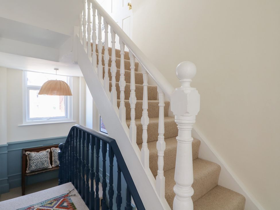 A hallway with stairs and a decorative light at East Cliff Gardens in Folkestone
