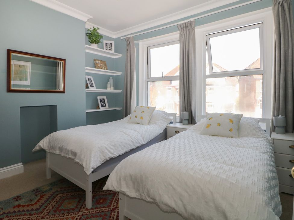 A bedroom with two beds and a mirror at East Cliff Gardens in Folkestone