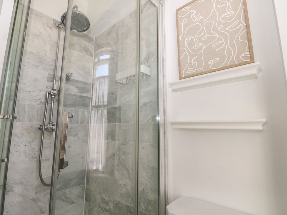 A shower with glass door and wall art at East Cliff Gardens in Folkestone