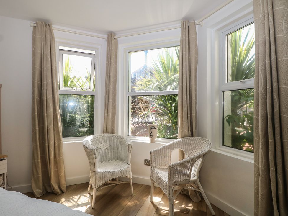 A sitting room with two white chairs and windows at East Cliff Gardens in Folkestone
