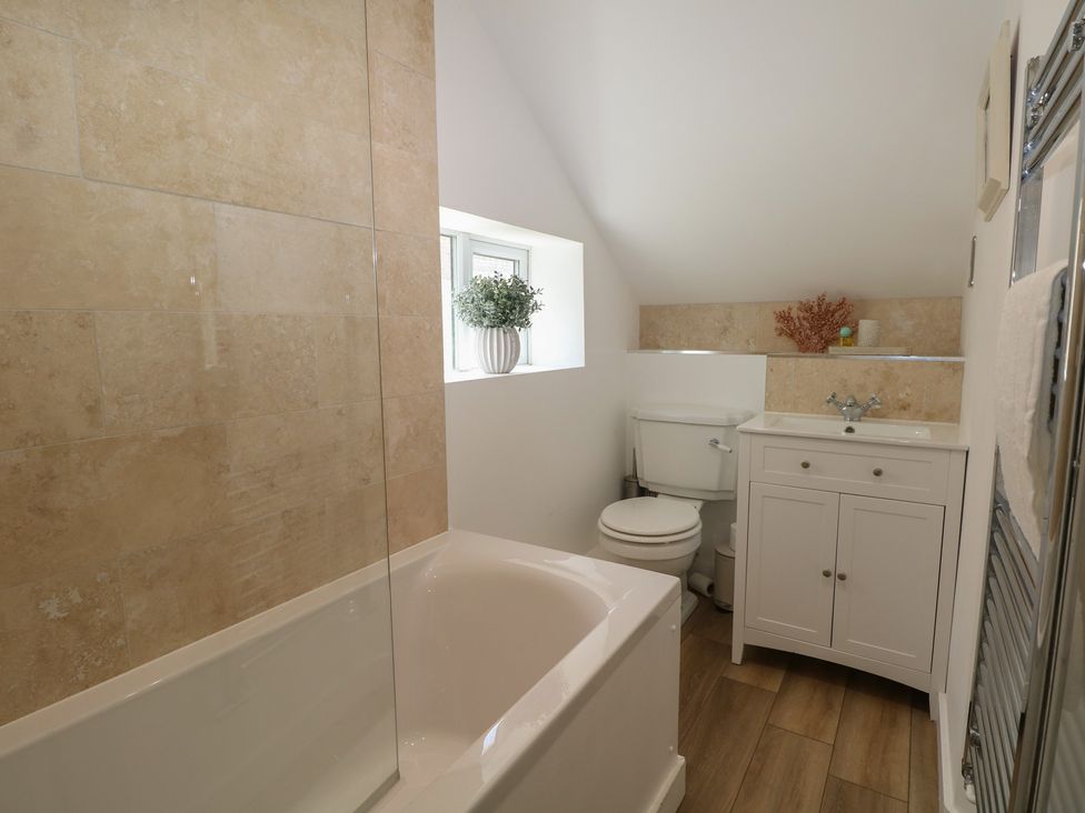 A bathroom featuring a bathtub, toilet, sink, and window at East Cliff Gardens in Folkestone