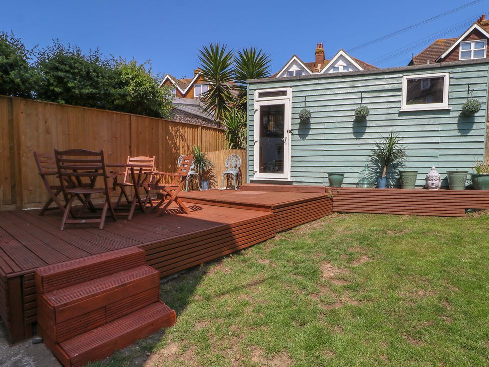 A garden with decking, table, and chairs at East Cliff Gardens in Folkestone