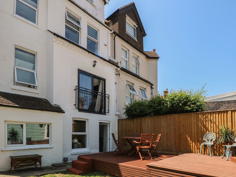 A garden with a deck, table, and chairs at East Cliff Gardens in Folkestone