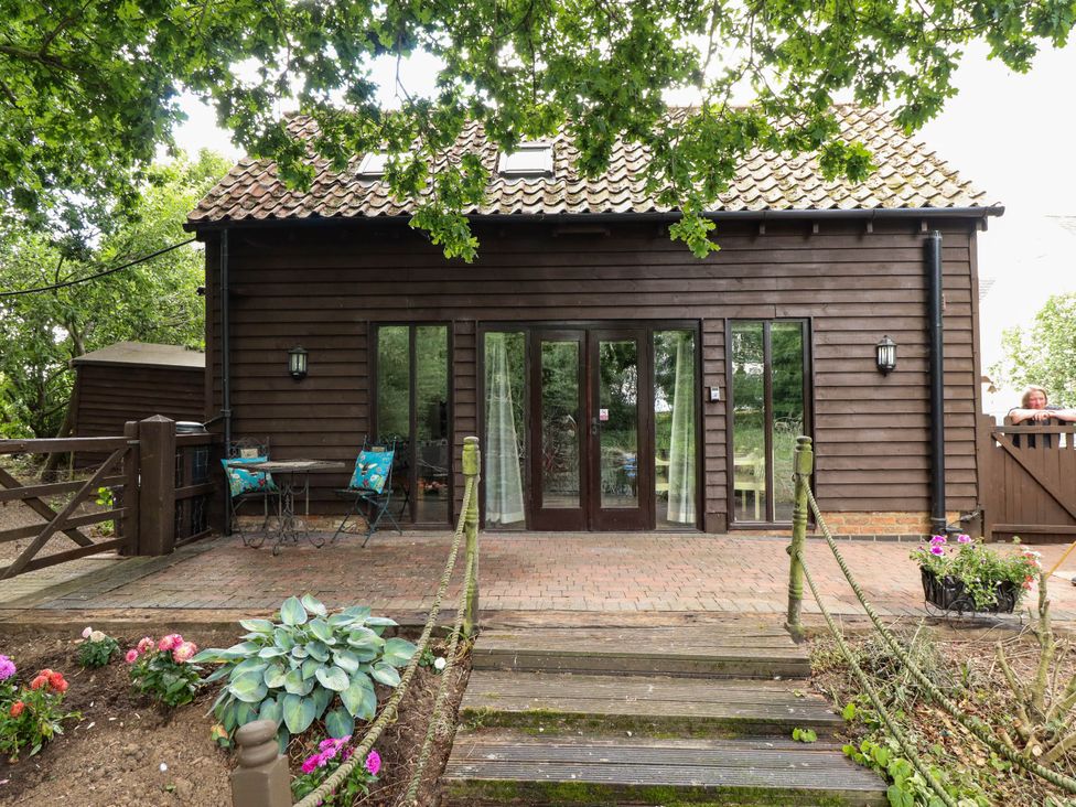 An outdoor view of a house with a porch and garden at Willow Tree Barn in Spalding