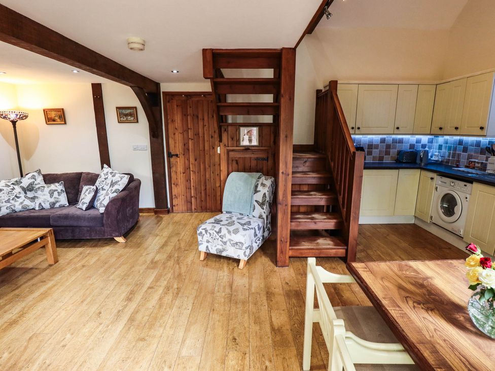 A living room with a staircase and kitchen area at Willow Tree Barn in Spalding