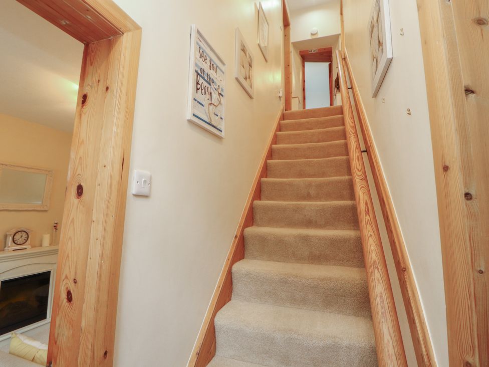 A hallway with stairs and paintings on the wall at The Haven in Heysham