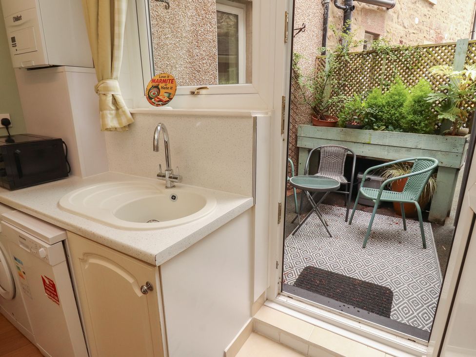 A kitchen with a sink and microwave leading to a garden area at The Haven in Heysham