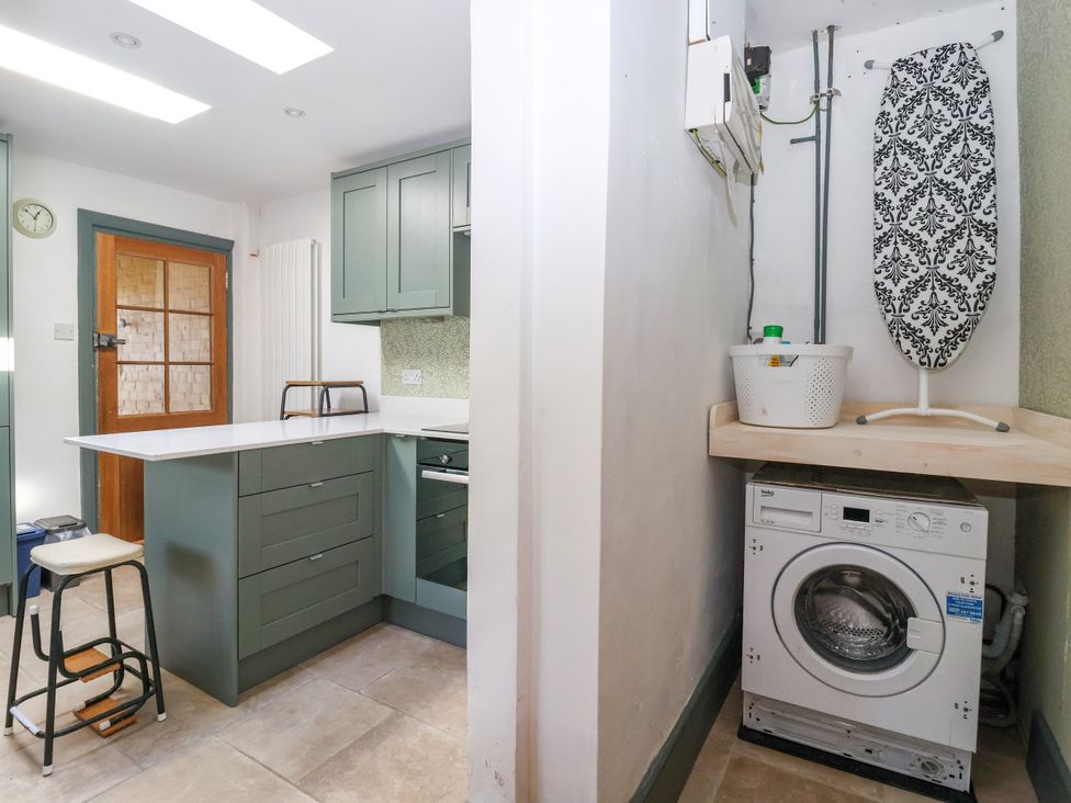 A kitchen with a washing machine and ironing board at Old Post Office