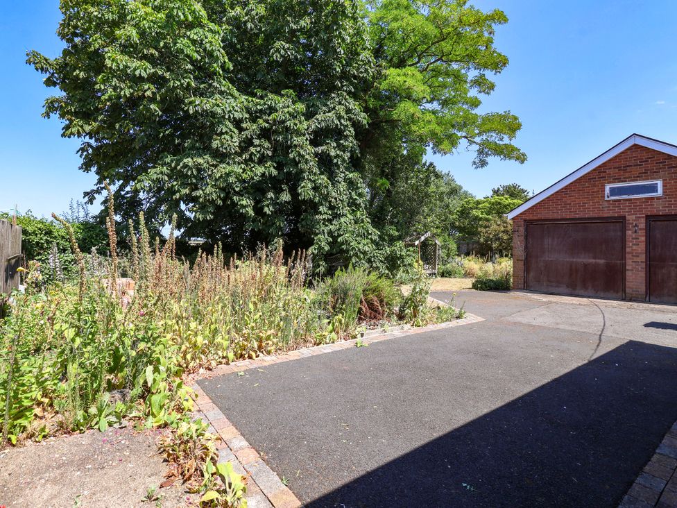 A driveway with a garage and greenery at the Old Post Office
