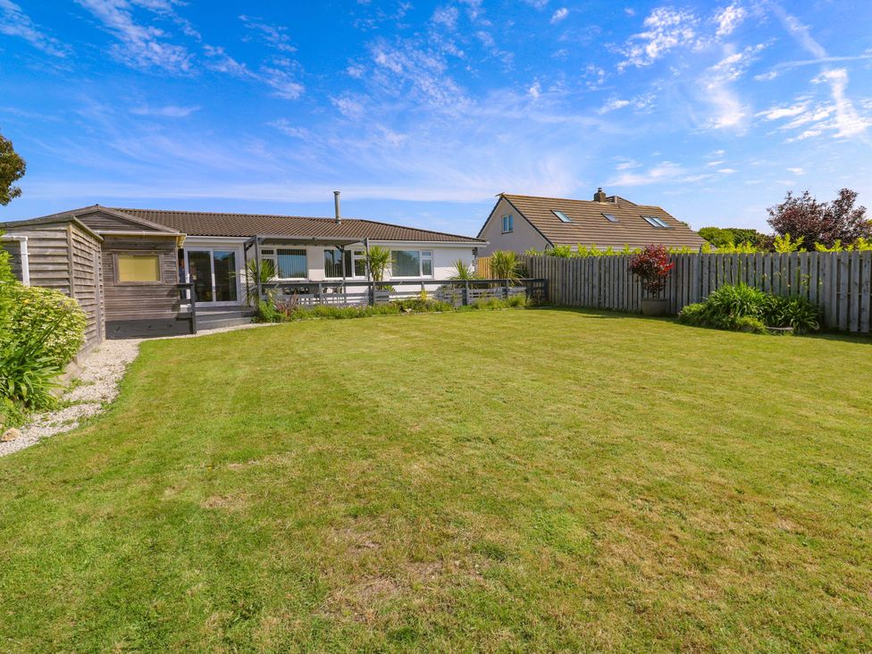 A garden with a lawn and a house in the background at Agan Paradhis in Quintrell Downs