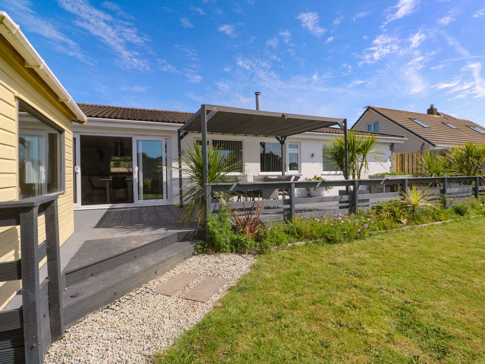 An outdoor area with a house, deck, table, and plants at Agan Paradhis in Quintrell Downs