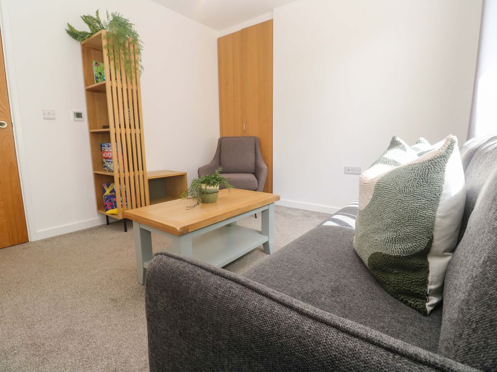 A living room with a sofa, chair, and bookshelf at Agan Paradhis in Quintrell Downs