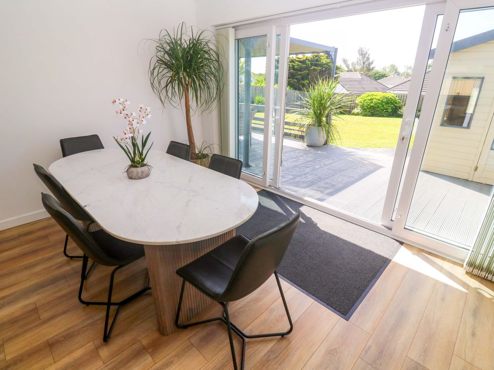 A dining room with a round table and black chairs at Agan Paradhis in Quintrell Downs