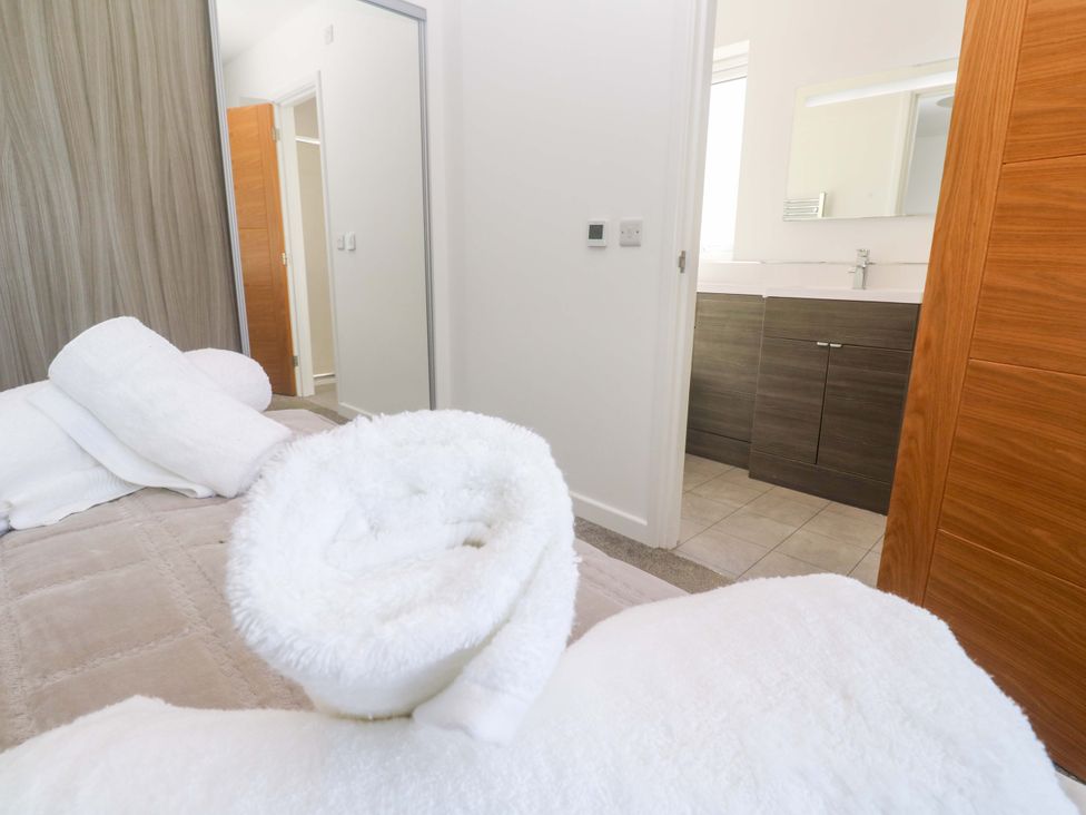 A bedroom with towels on the bed and a vanity with a sink at Agan Paradhis in Quintrell Downs