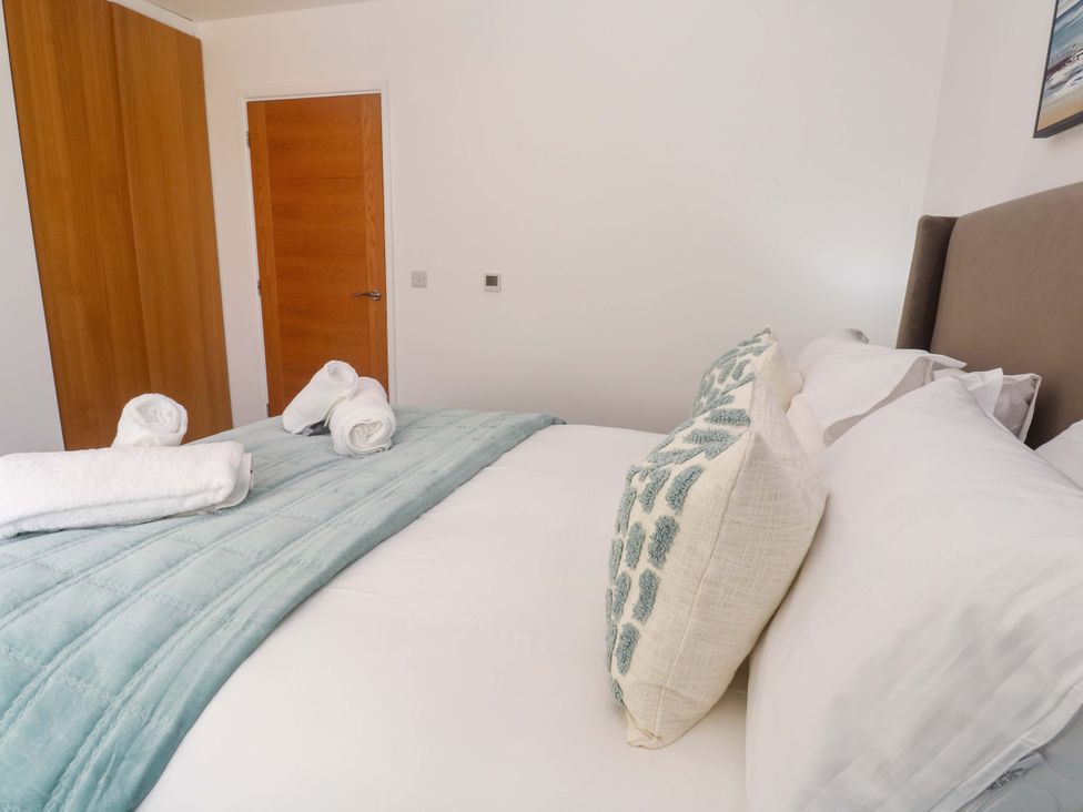 A bedroom with a bed and towels neatly arranged at Agan Paradhis in Quintrell Downs